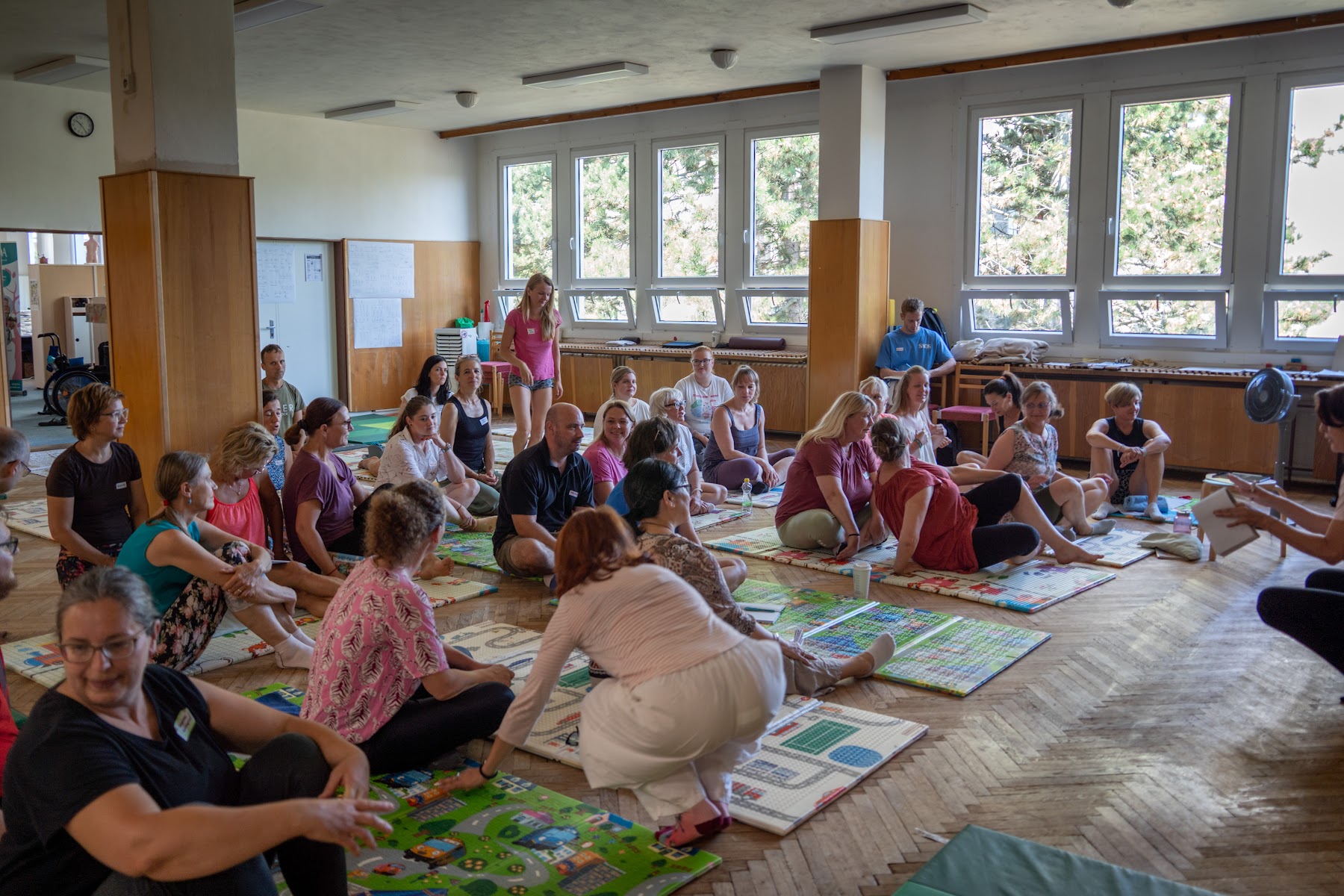 Účastníci workshopu Empowering Parents sedí na podložkách v sále v Hradci Králové