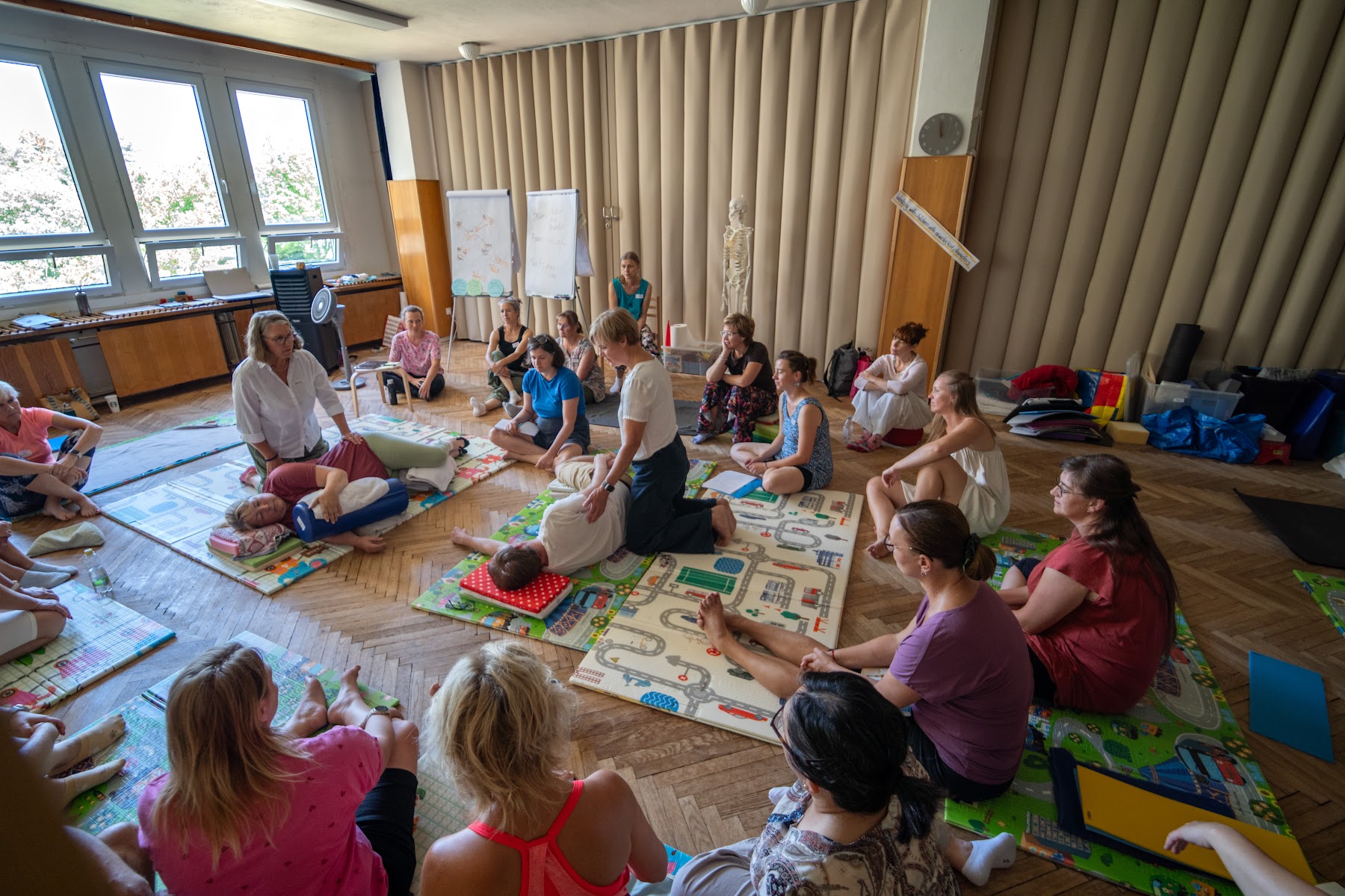 Rodiče a odborníci sedí v kruhu na podložkách při společné diskusi během workshopu Empowering Parents