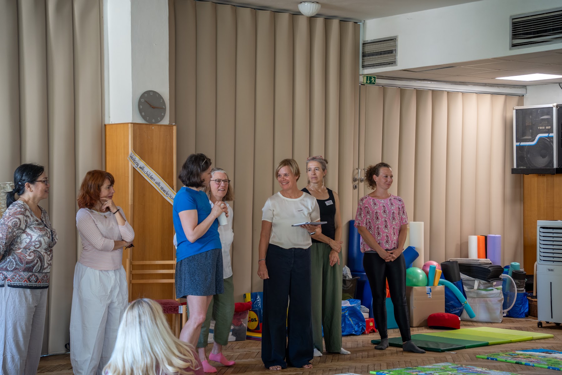 Lektorský a tlumočnický tým stojí před účastníky workshopu v sále v Hradci Králové